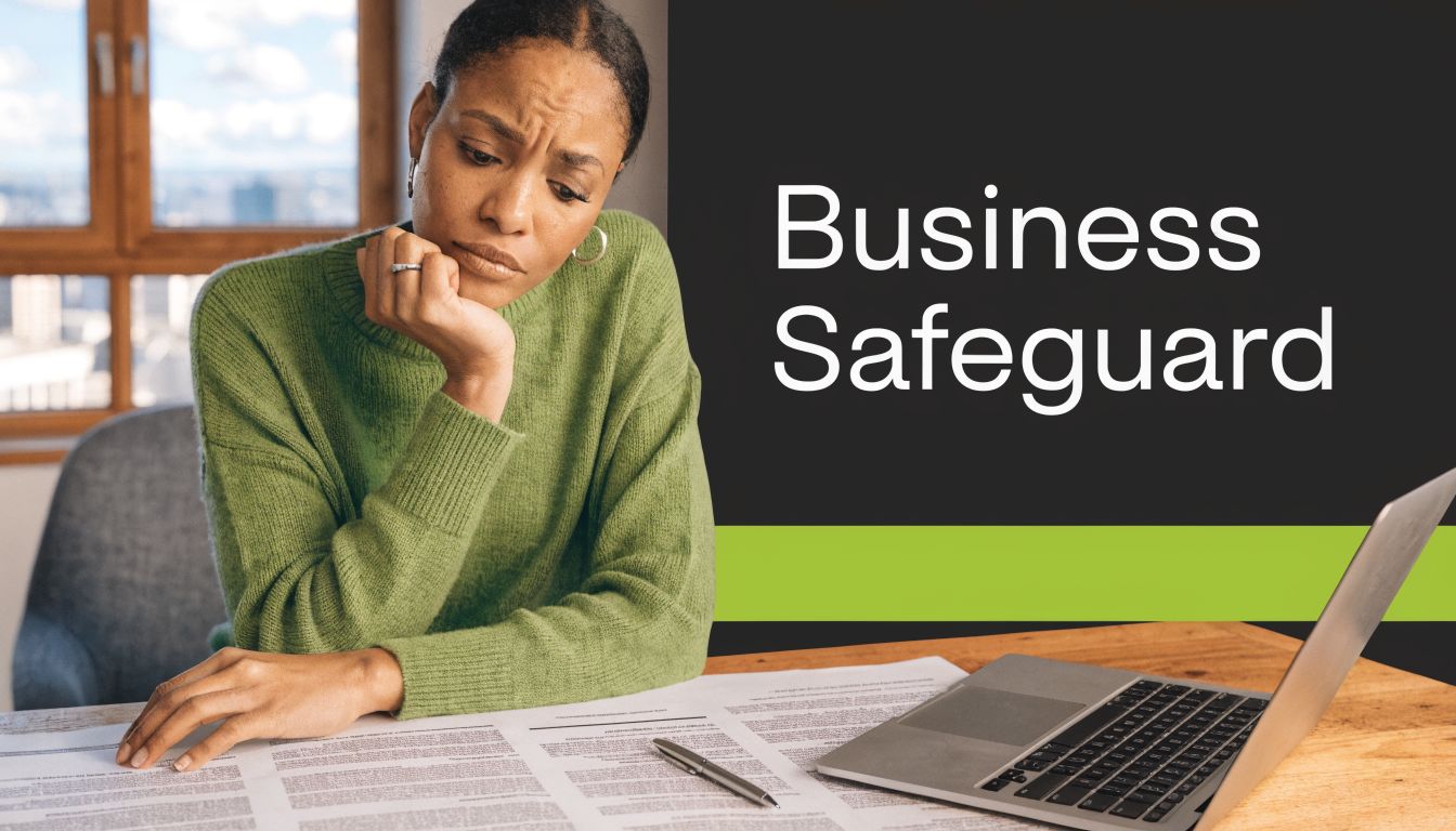 A focused woman in a green sweater reviewing a business contract next to her open laptop.