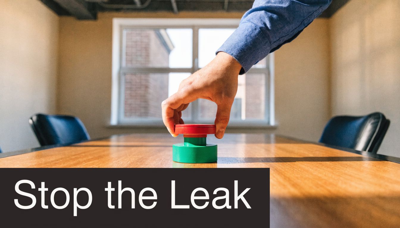 A hand pressing a red and green button on a desk to symbolize stopping a information leak.