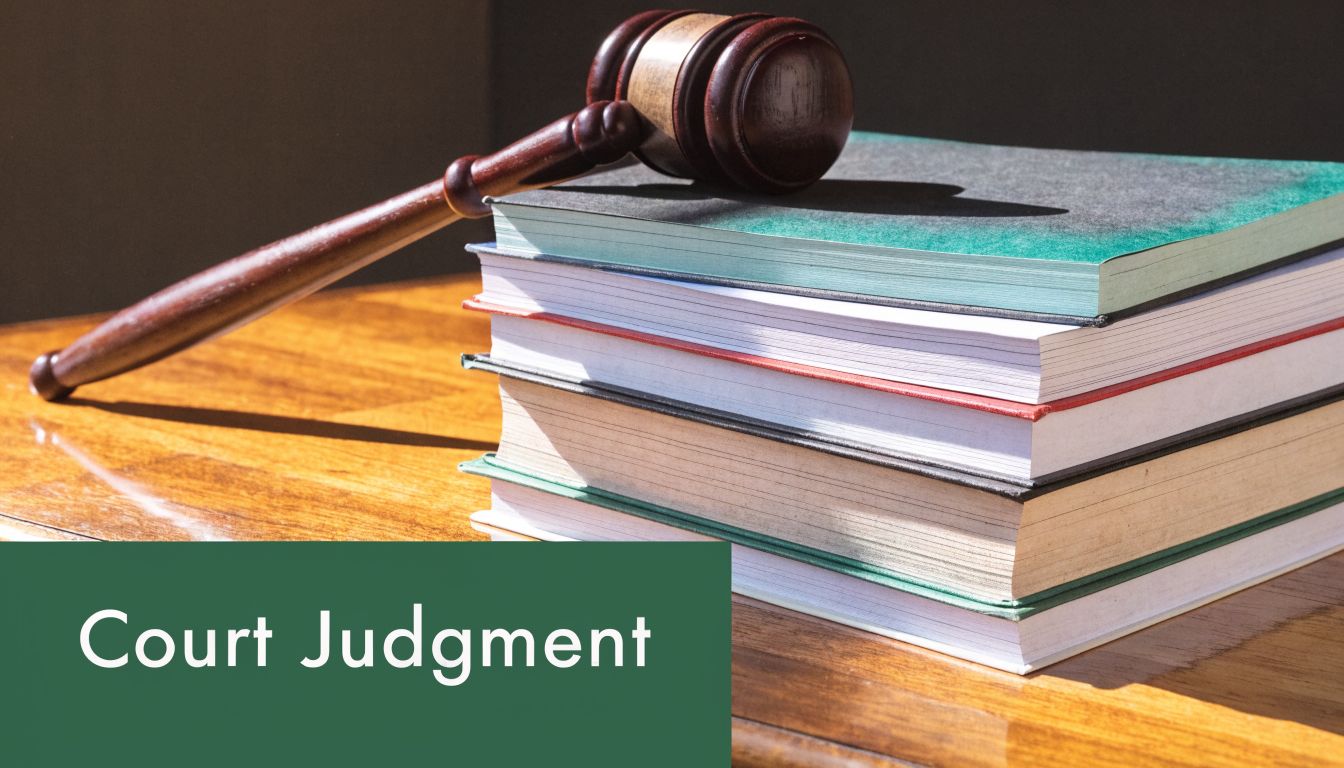A wooden judge's gavel resting on a stack of legal law books on a desk.